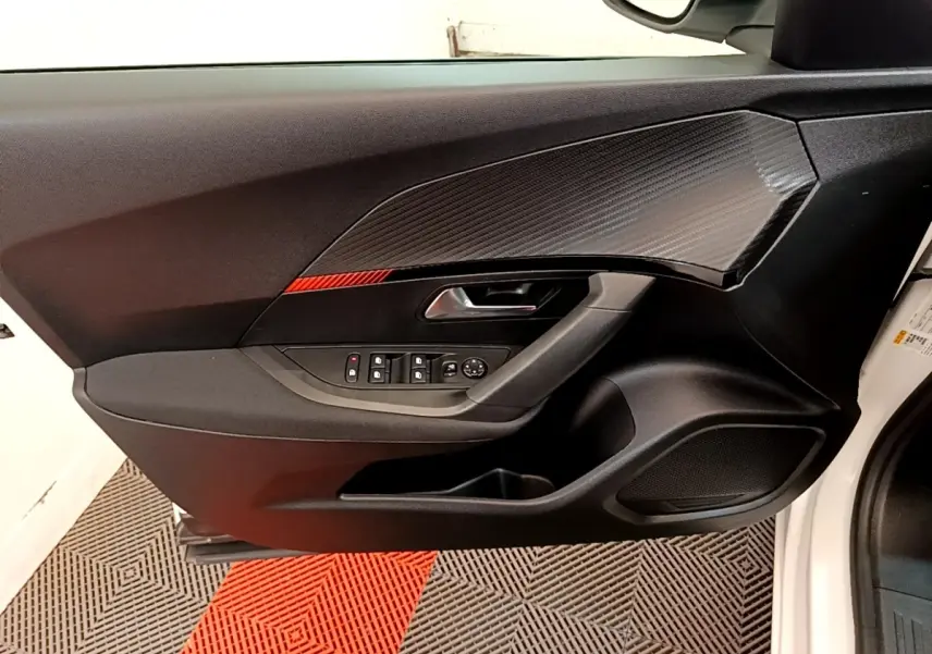 Vue intérieure du panneau de porte côté conducteur du Peugeot 2008 blanc, avec commandes électriques et insert décoratif noir.