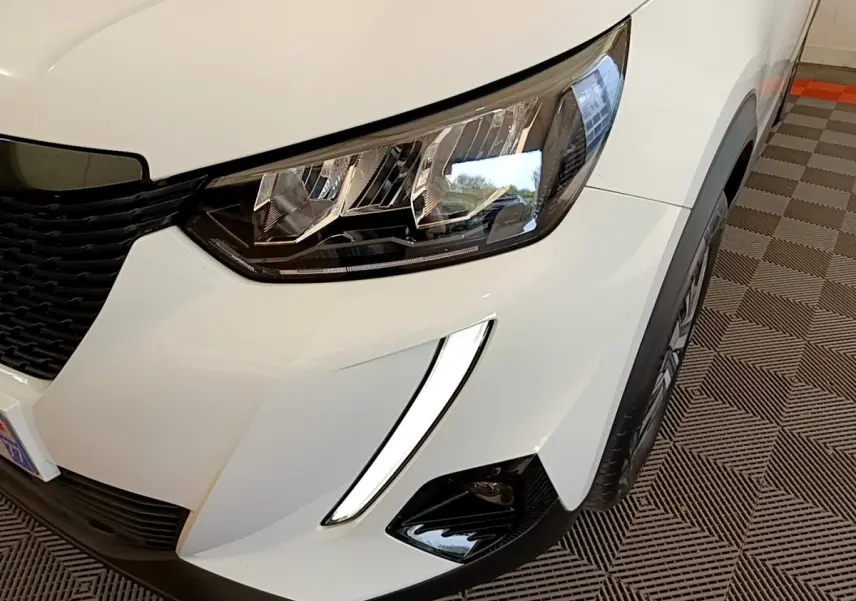 Gros plan sur l'avant droit blanc du Peugeot 2008 2021 avec phares LED et feux diurnes en forme de griffes.