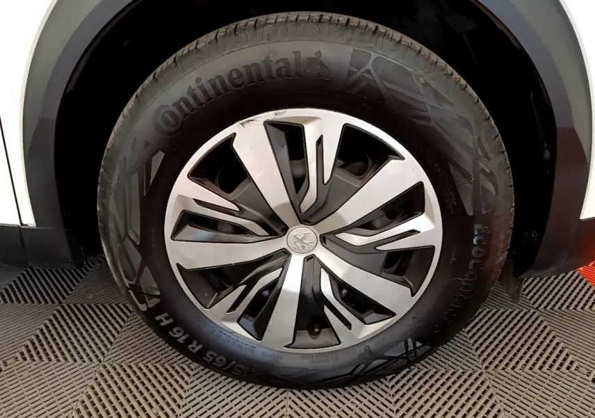 Gros plan sur la roue avant droite d’un Peugeot 2008 blanc, jante alliage à design moderne et pneu Continental.
