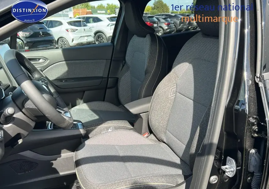 Vue intérieure côté conducteur du Renault Captur noir étoile 2025, mettant en valeur les sièges tissu gris et l'accoudoir central.