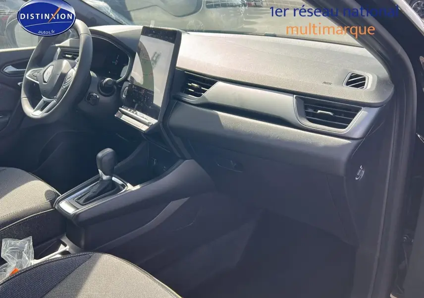 Intérieur avant du Renault Captur 1.6 e-tech hybride 2025, tableau de bord moderne avec écran tactile vertical et volant multifonction.