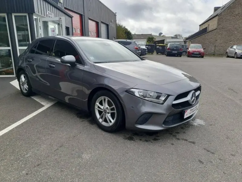 Mercedes Classe A 160 109ch Style Line gris montagne métallisé vue 3/4 avant avec jantes alu et vitres teintées.