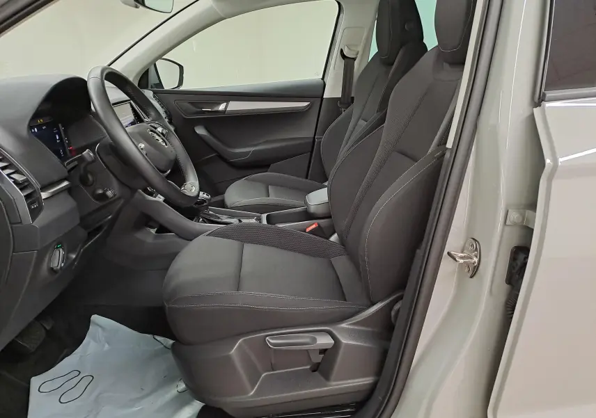 Vue intérieure côté conducteur du Skoda Karoq gris perle 2023, mettant en valeur les sièges noirs et le tableau de bord digital.
