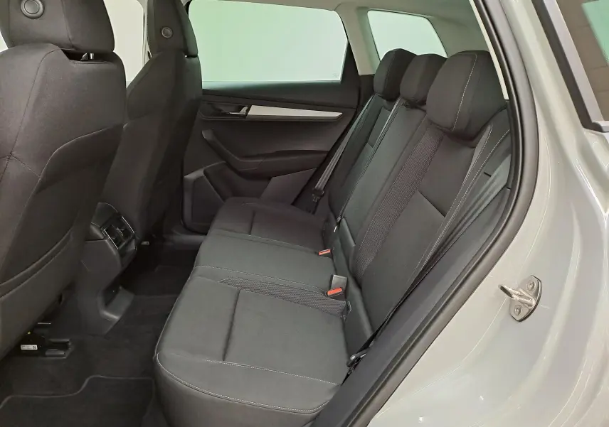 Vue latérale droite de l'habitacle arrière du Skoda Karoq gris perle, montrant les sièges en tissu noir et les finitions intérieures.