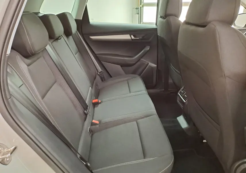 Vue intérieure côté gauche des sièges arrière noirs du Skoda Karoq 2023 avec finitions sobres et ceintures de sécurité visibles.