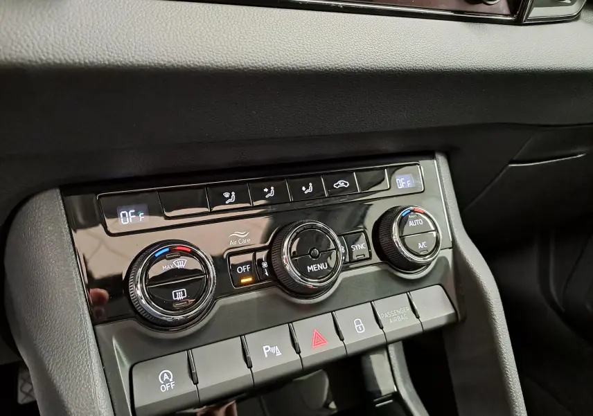 Gros plan sur la console centrale du Skoda Karoq 2023, montrant les commandes de climatisation et les boutons de fonction.