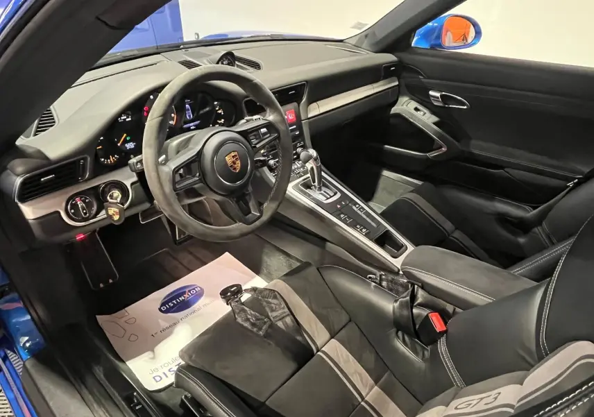 Vue intérieure côté conducteur de la Porsche 911 GT3 bleu saphir, volant sport alcantara et sièges baquets GT3.