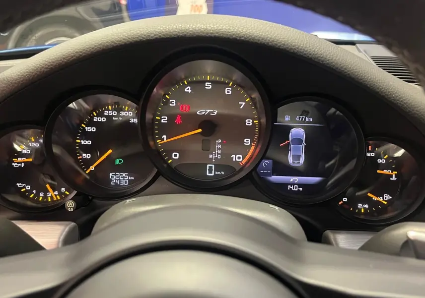 Vue rapprochée du tableau de bord de la Porsche 911 GT3, affichant le compteur central GT3 et l'écran digital.