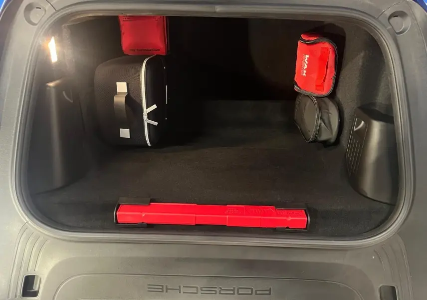 Vue intérieure du coffre avant d'une Porsche 911 GT3 bleu saphir avec trousse de secours et triangle de signalisation rouge.