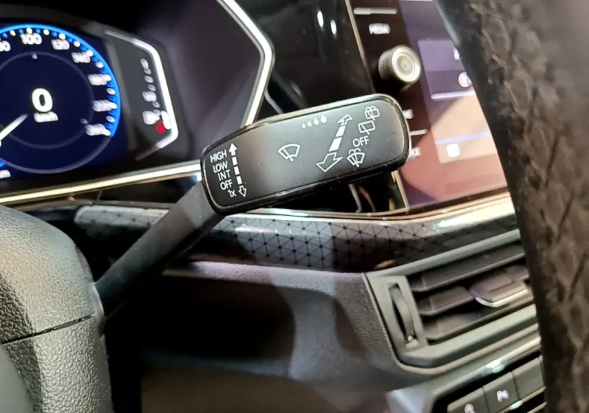 Gros plan sur la manette d’essuie-glace à gauche du volant dans l’habitacle noir du Volkswagen T-Cross 2022.