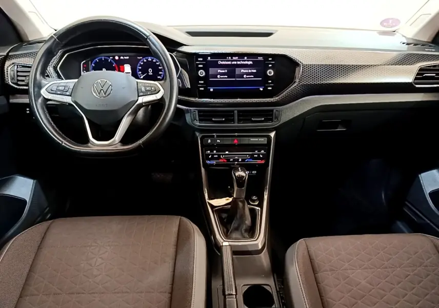 Vue intérieure avant du Volkswagen T-Cross 2022 noir, montrant le volant multifonctions, tableau de bord digital et console centrale.
