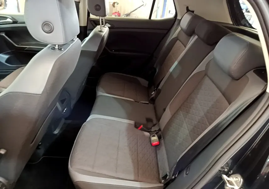 Vue intérieure côté droit sur la banquette arrière grise du Volkswagen T-Cross noir, avec portes ouvertes.