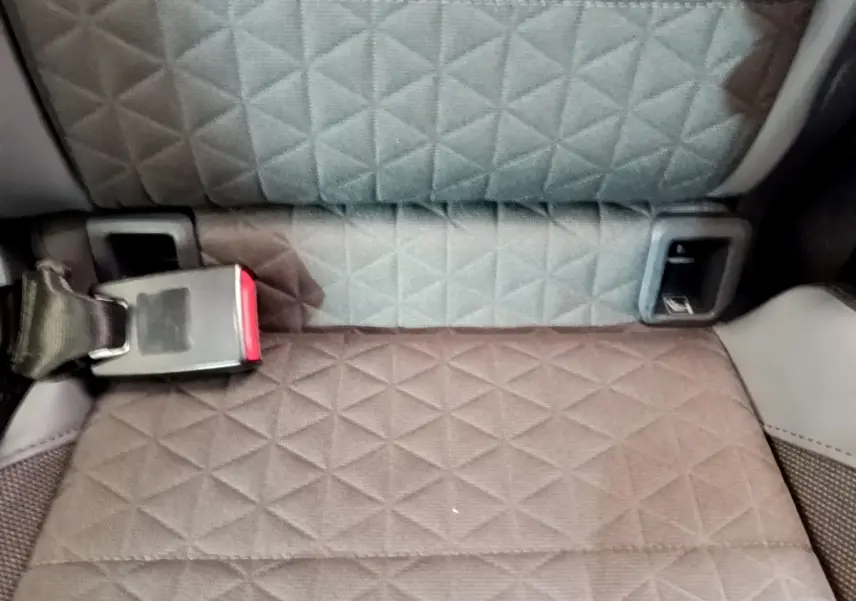 Gros plan sur la banquette arrière grise à motif losange du Volkswagen T-Cross noir, avec ceinture de sécurité visible.