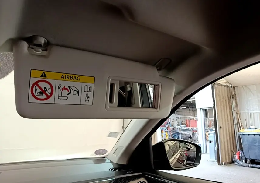 Vue intérieure du pare-soleil côté conducteur avec miroir et avertissement airbag dans un Volkswagen T-Cross noir 2022.