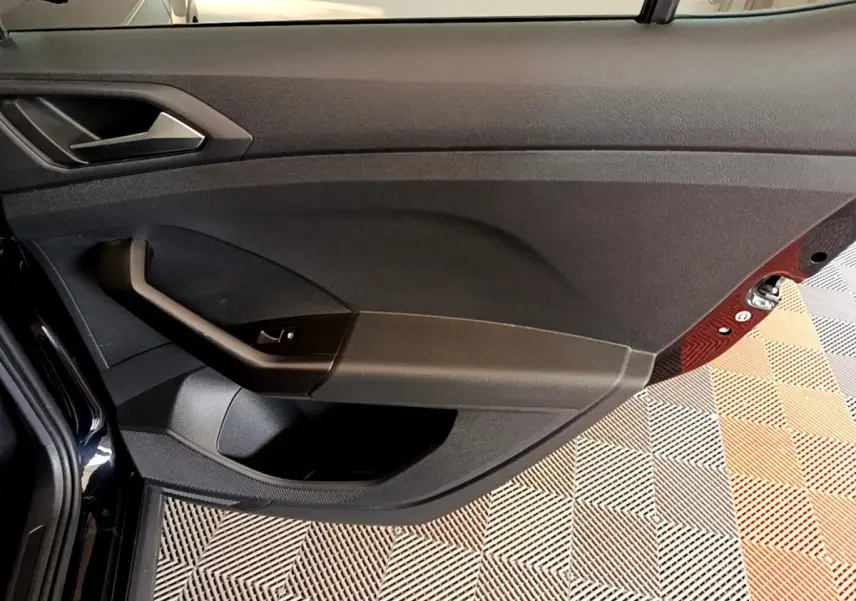 Intérieur de la porte côté conducteur du Volkswagen T-Cross noir, avec commande de vitre et poignée intégrée.