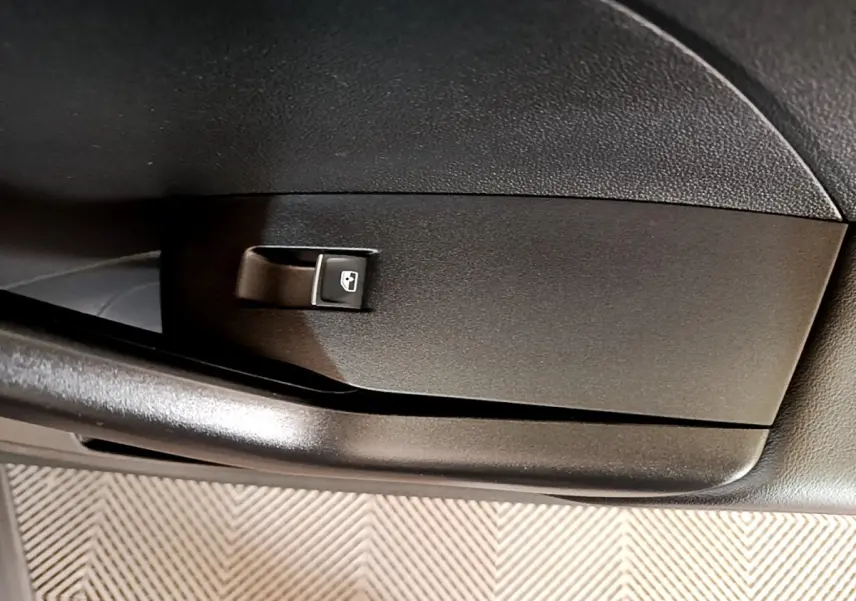 Gros plan sur la commande de lève-vitre arrière noire dans l'habitacle du Volkswagen T-Cross noir.