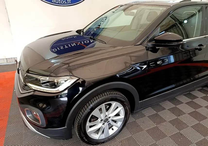 Vue 3/4 avant droit d'un Volkswagen T-Cross noir brillant, mettant en valeur ses phares LED et jantes alliage.