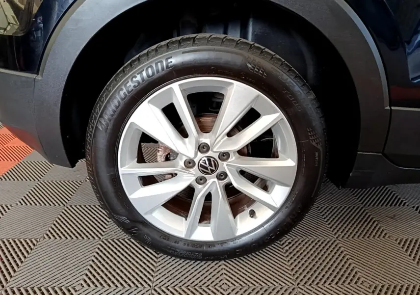 Gros plan sur la roue avant droite d’un Volkswagen T-Cross noir, jante alliage argentée et pneu Bridgestone.