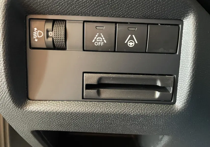 Gros plan sur les commandes noires du tableau de bord du Citroën C5 Aircross gris platinium, boutons d'assistance à la conduite visibles.