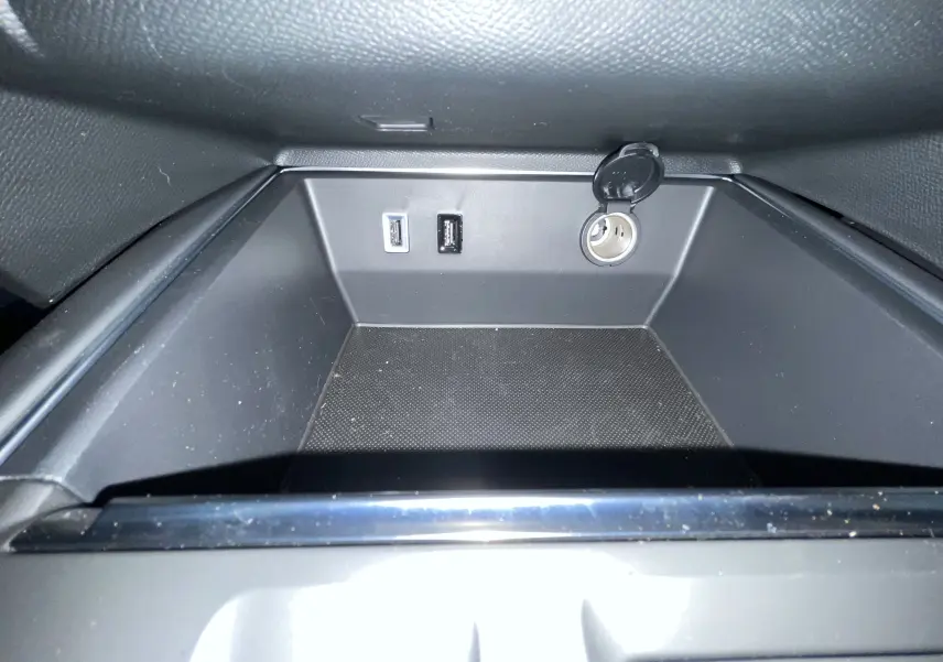 Gros plan sur la prise 12V et ports USB dans le rangement intérieur du Citroën C5 Aircross hybride gris platinium.