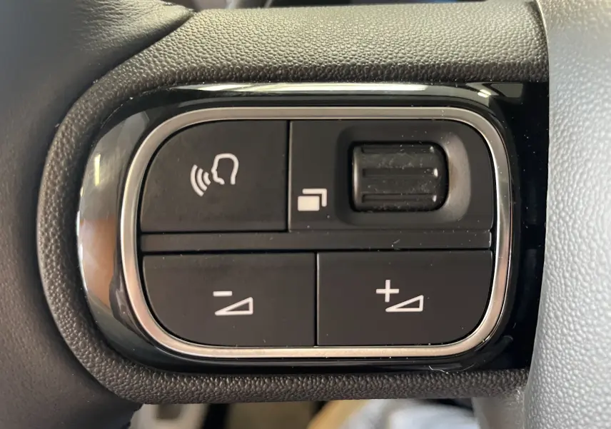 Gros plan sur les commandes au volant du Citroën C5 Aircross hybride gris platinium, avec boutons de volume et fonction mains libres.