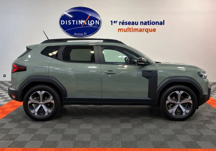 Profil côté droit du Dacia Duster 2026 vert cèdre, version hybride, avec jantes alliage et détails noirs contrastants.