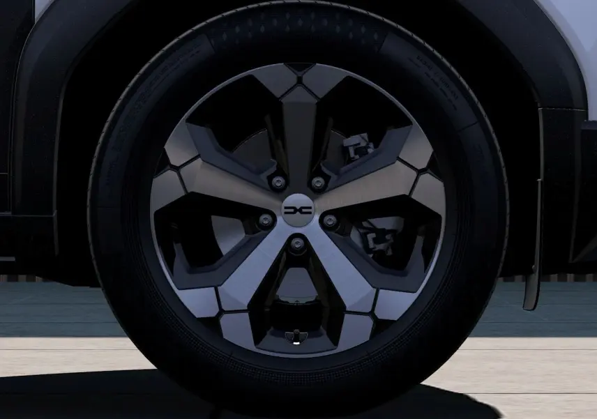 Gros plan sur la roue avant droite du Dacia Duster 2026, jante alliage noire et argentée, partie basse du véhicule blanche visible.