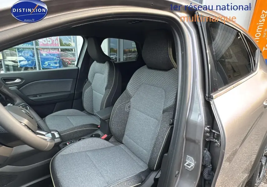 Intérieur avant du Renault Captur gris cassiopée 2025, sièges tissu gris et accoudoir central visible côté droit.