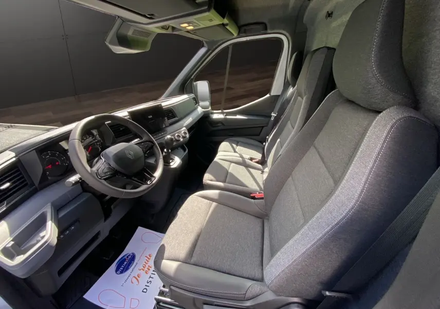 Vue intérieure côté conducteur du Renault Master 2025, montrant la sellerie tissu gris foncé et le tableau de bord moderne.