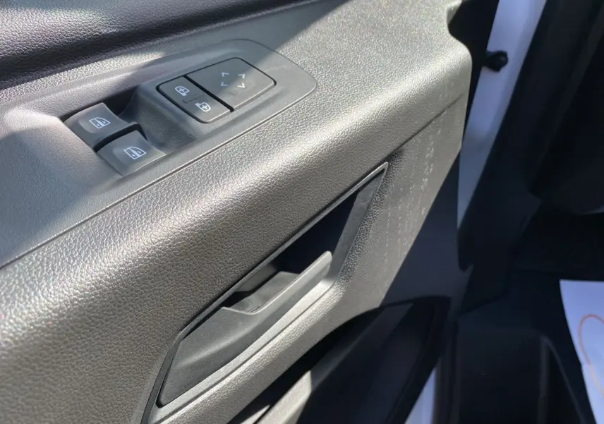 Poignée et commandes des vitres côté conducteur du Renault Master blanc 2025, intérieur en plastique noir texturé.