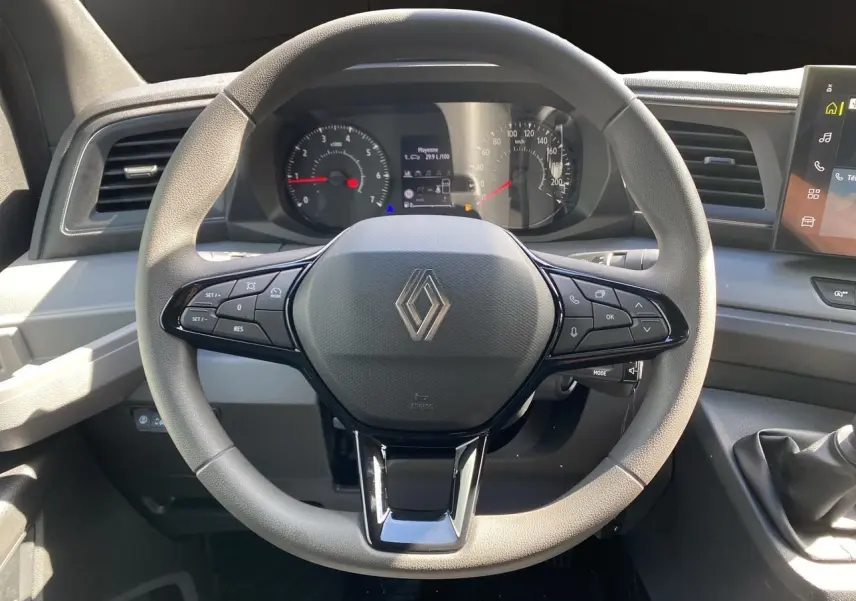 Vue rapprochée du volant gris et noir avec logo Renault, tableau de bord et levier de vitesse manuel du Master 2025.