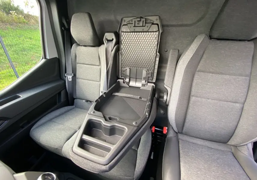 Intérieur du Renault Master 2025 montrant la banquette passager grise avec bureau mobile déplié entre les sièges avant.