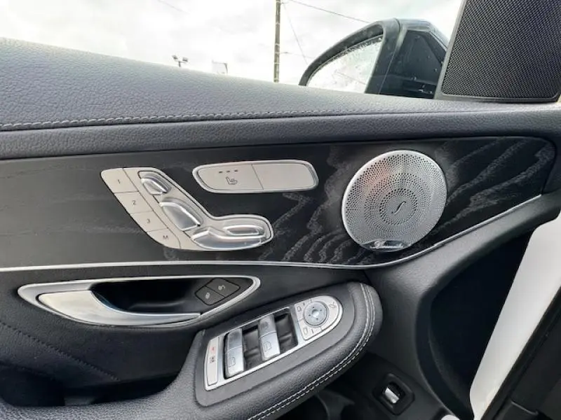 Détail de la porte avant gauche du Mercedes GLC Coupé blanc polaire avec inserts frêne noir et commandes en aluminium.