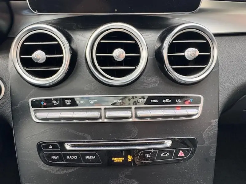 Gros plan sur la console centrale noire du Mercedes GLC Coupé 350 d avec aérateurs ronds chromés et commandes climatisation.