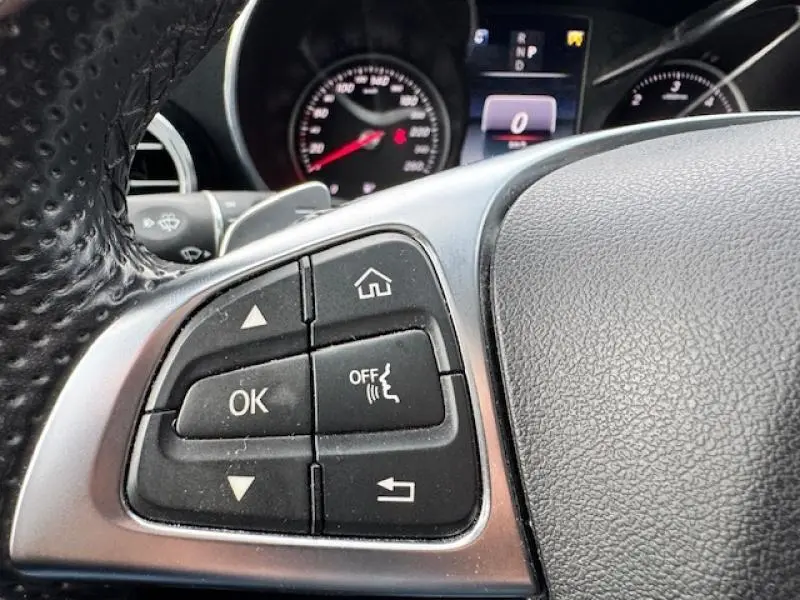 Gros plan sur les commandes multifonctions à gauche du volant cuir noir du Mercedes GLC Coupé blanc polaire 2017.