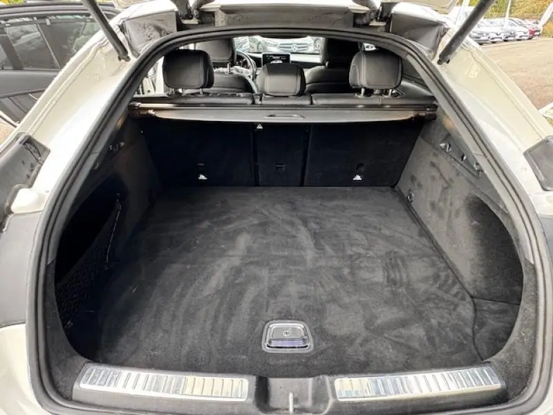 Coffre ouvert vu de l'arrière d'un Mercedes GLC Coupé blanc polaire avec intérieur noir et cache-bagages.