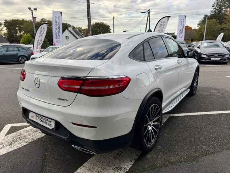 Vue 3/4 arrière droite d'un Mercedes GLC Coupé blanc polaire avec jantes alu et feux arrière LED distinctifs.