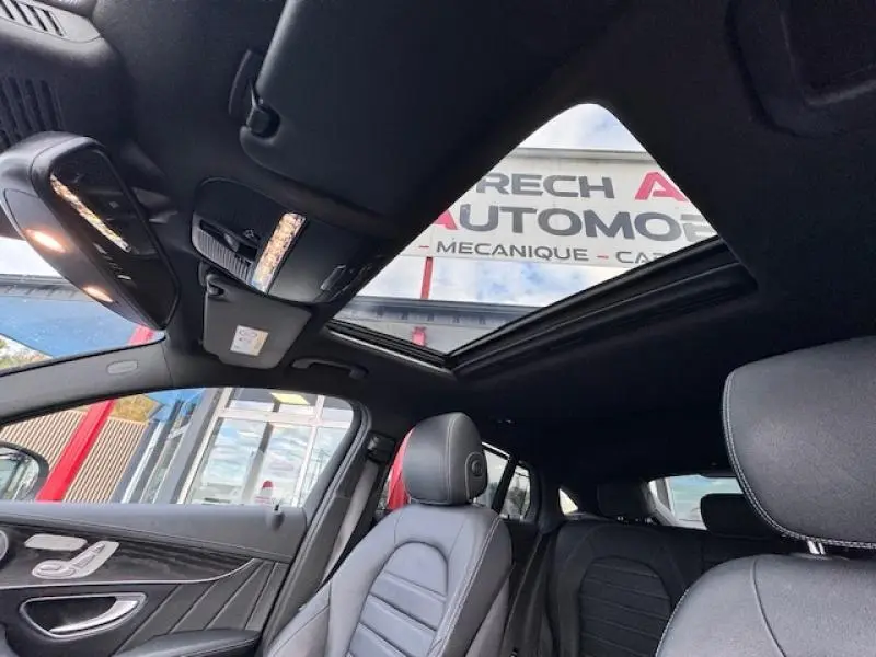 Intérieur noir du Mercedes GLC Coupé 350 d 2017, vue sur sièges avant et toit ouvrant panoramique ouvert.