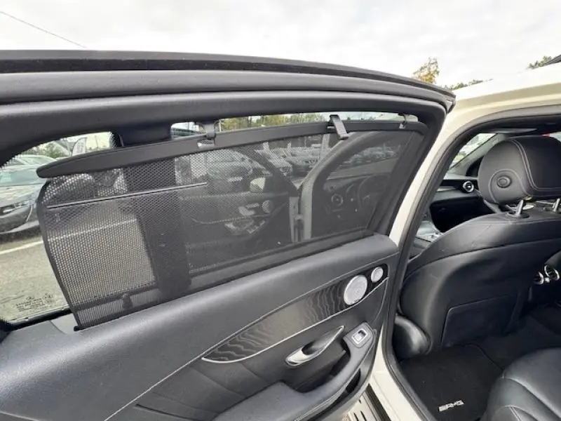 Vue intérieure côté gauche arrière du Mercedes GLC Coupé blanc polaire, avec pare-soleil et sellerie cuir noir visible.