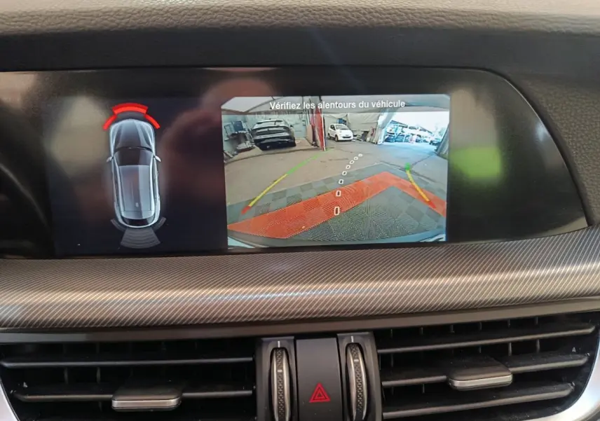 Écran central de l'Alfa Romeo Stelvio gris foncé montrant la caméra de recul avec aide au stationnement arrière.