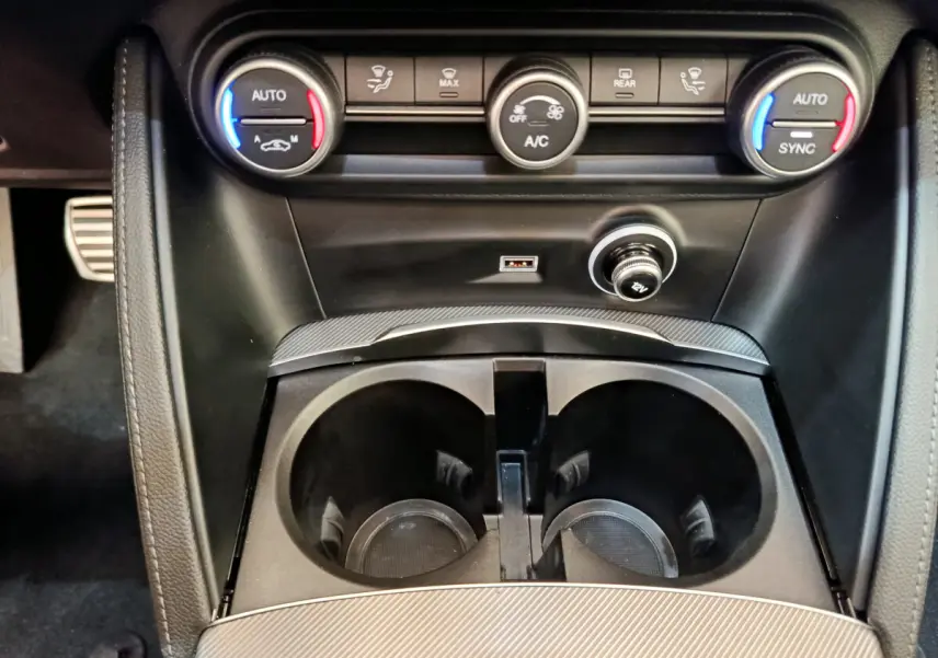 Gros plan sur la console centrale noire avec commandes climatisation bi-zone et prises USB du Alfa Romeo Stelvio Sprint 2024.