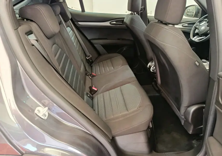 Vue intérieure côté gauche sur la banquette arrière grise foncée de l'Alfa Romeo Stelvio 2024 avec sièges tissu et appuie-têtes.