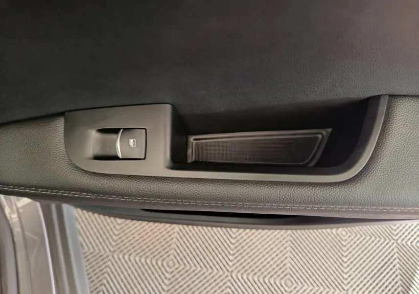 Détail de la commande de lève-vitre sur la porte intérieure côté gauche de l'Alfa Romeo Stelvio gris foncé 2024.