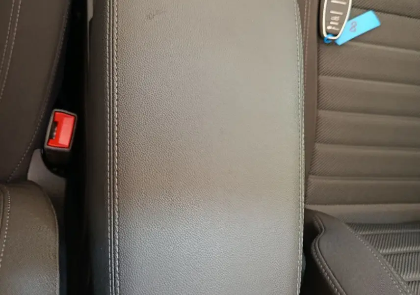 Vue plongeante sur l'accoudoir central en cuir noir et siège tissu gris foncé avec clé de voiture Alfa Romeo Stelvio.