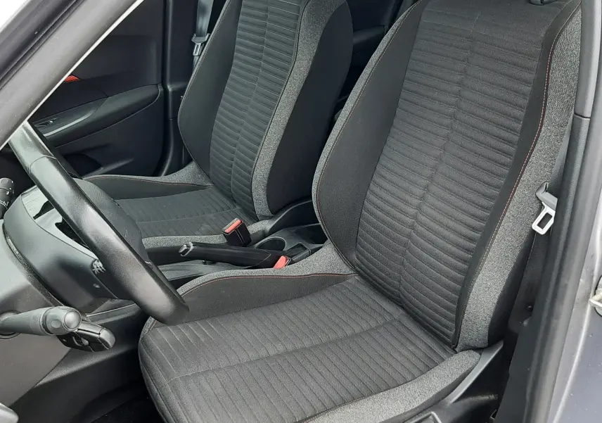 Vue intérieure côté conducteur du Peugeot 2008 gris Artense 2020, sièges tissu gris foncé avec surpiqûres rouges.