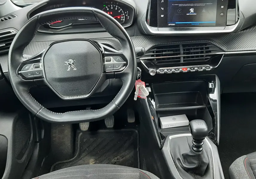 Vue intérieure avant du Peugeot 2008 2020, tableau de bord gris avec volant compact, écran tactile et levier de vitesse manuel.