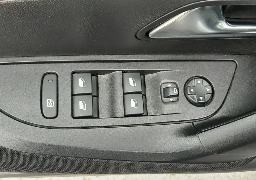Gros plan sur les commandes de lève-vitres et réglage des rétroviseurs côté conducteur d’un Peugeot 2008 gris Artense.