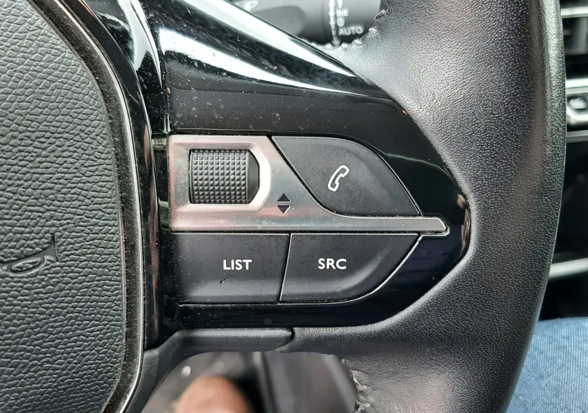 Gros plan sur les commandes gauche du volant noir du Peugeot 2008 2020, avec boutons LIST, SRC et symbole téléphone.