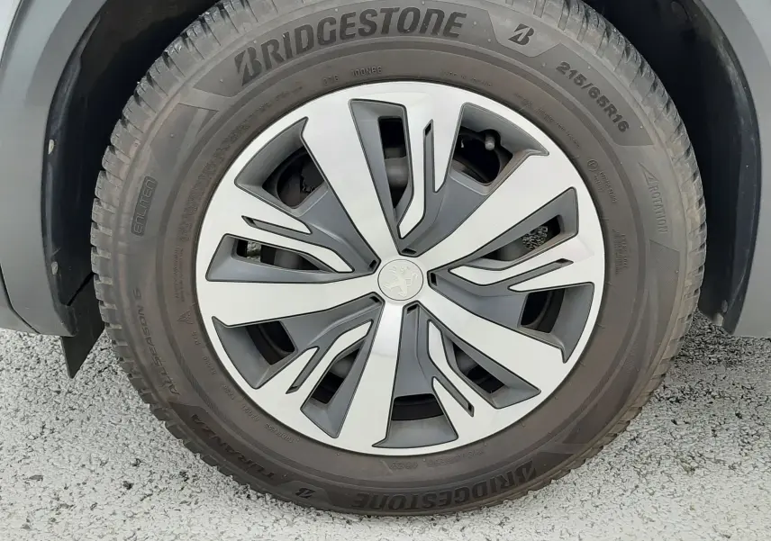 Gros plan sur la roue avant gauche d’un Peugeot 2008 gris Artense, jante alliage au design moderne et pneu Bridgestone.