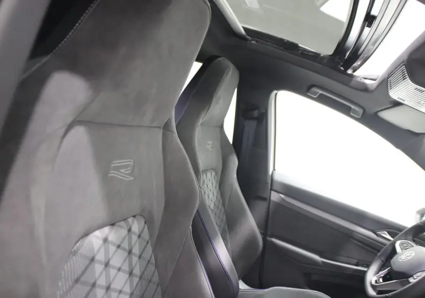 Vue intérieure côté gauche montrant les sièges sport noirs avec logo R et le toit panoramique ouvert.